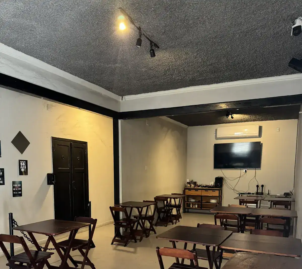 Ambiente para aniversário no Zora Bar em Santos, com mesas de madeira e TV