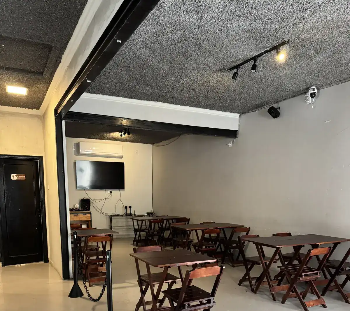 Espaço para eventos do Zora Bar no Gonzaga, em Santos, com mesas e iluminação de trilho