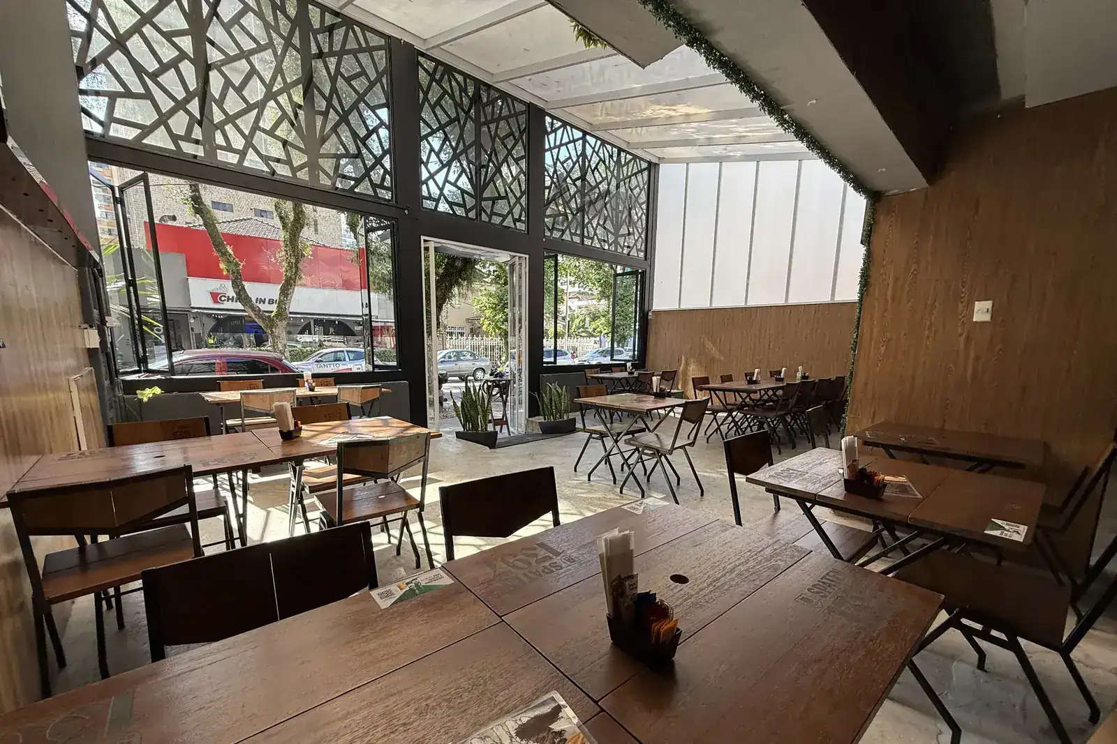 Salão do Zora Bar visto de dentro, com a fachada de vidro voltada para a rua gastronômica