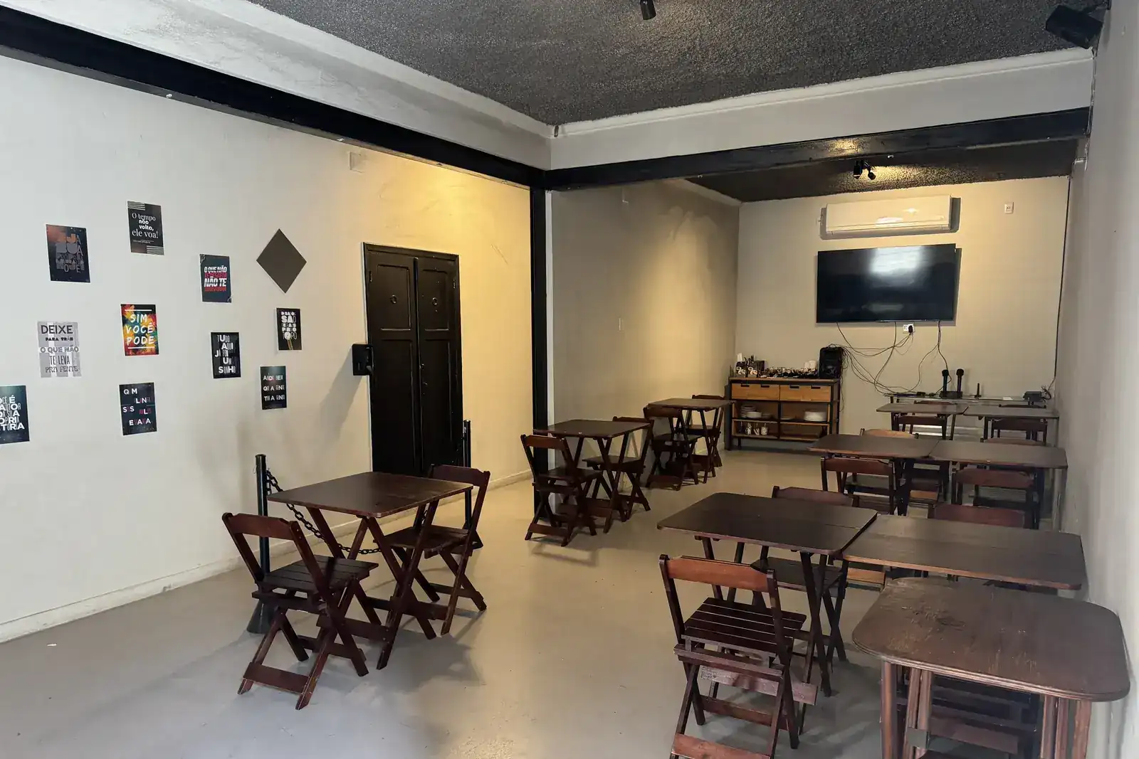 Vista do salão privativo para festas do Zora Bar, com painel decorativo e porta de acesso